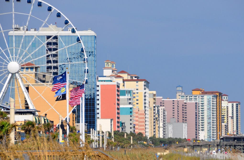 Color photograph of multicolored apartment towers and ferris wheel.