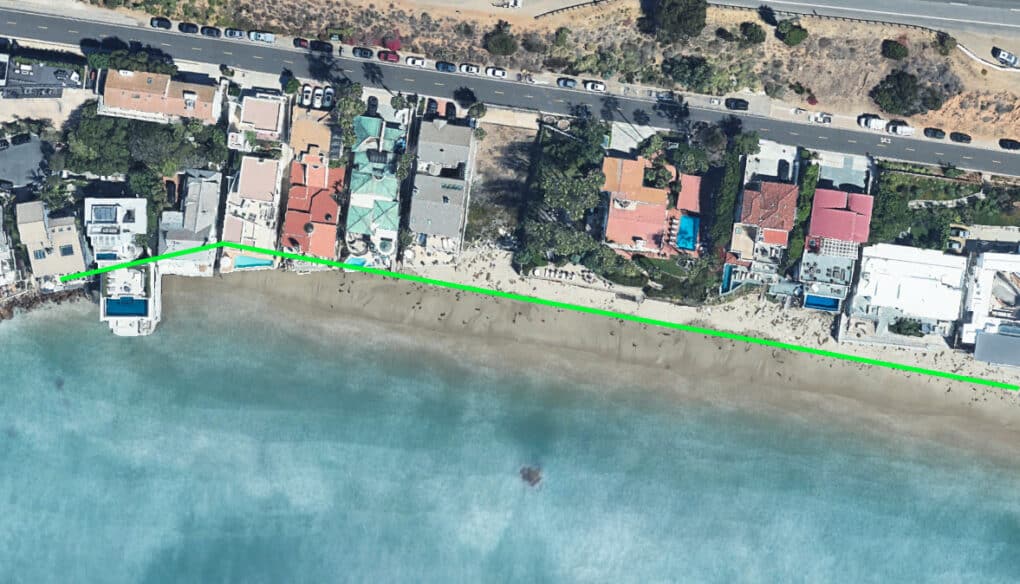 Aerial view, looking down on beachfront houses; a green line shows that parts of several houses are in the tide. 