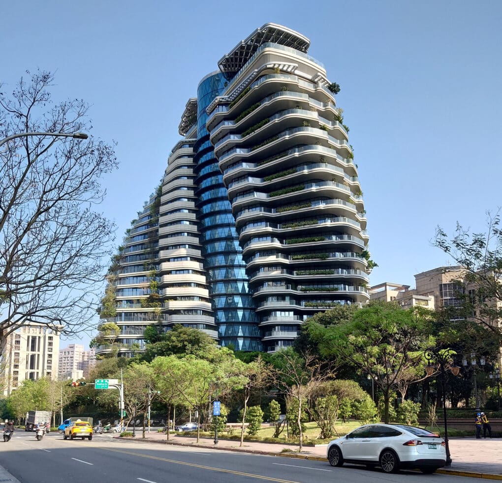 Color photograph of spiral-twisting apartment tower on tree-lined street.