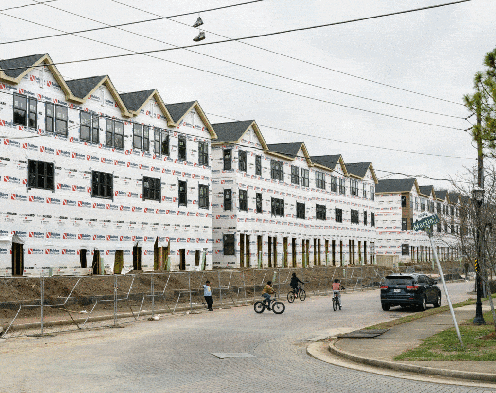 Peoplestown, Atlanta, Georgia, 2021. Photograph by Joshua Dudley Greer, depicting boys on bikes riding in front of a housing development under construction. 