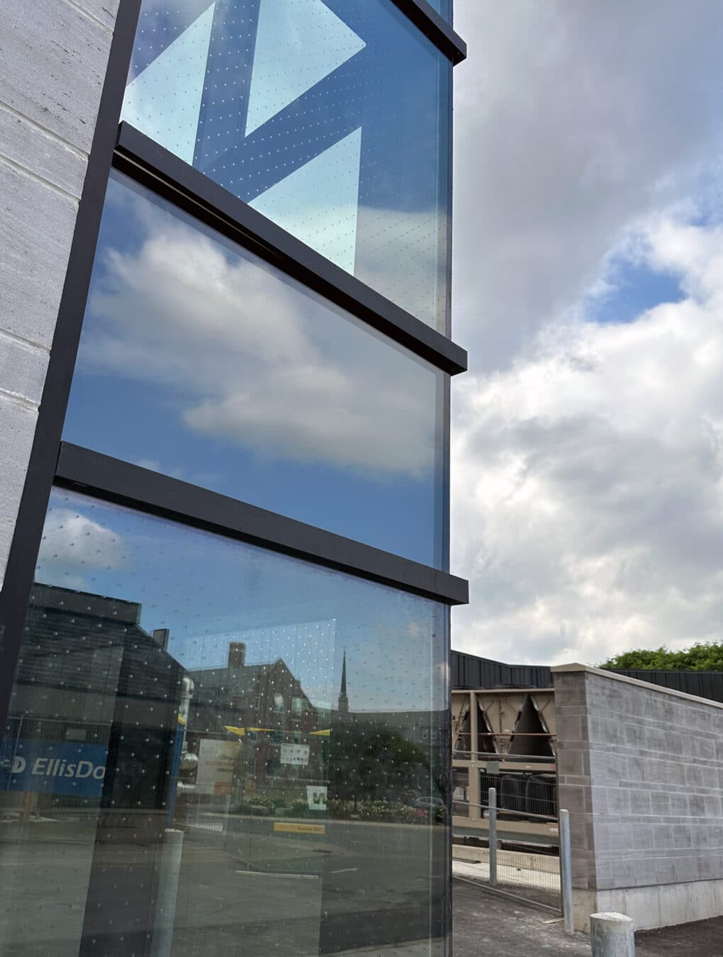 Color photograph of tinted glass windows with inset grid of white dots, in a concrete building.
