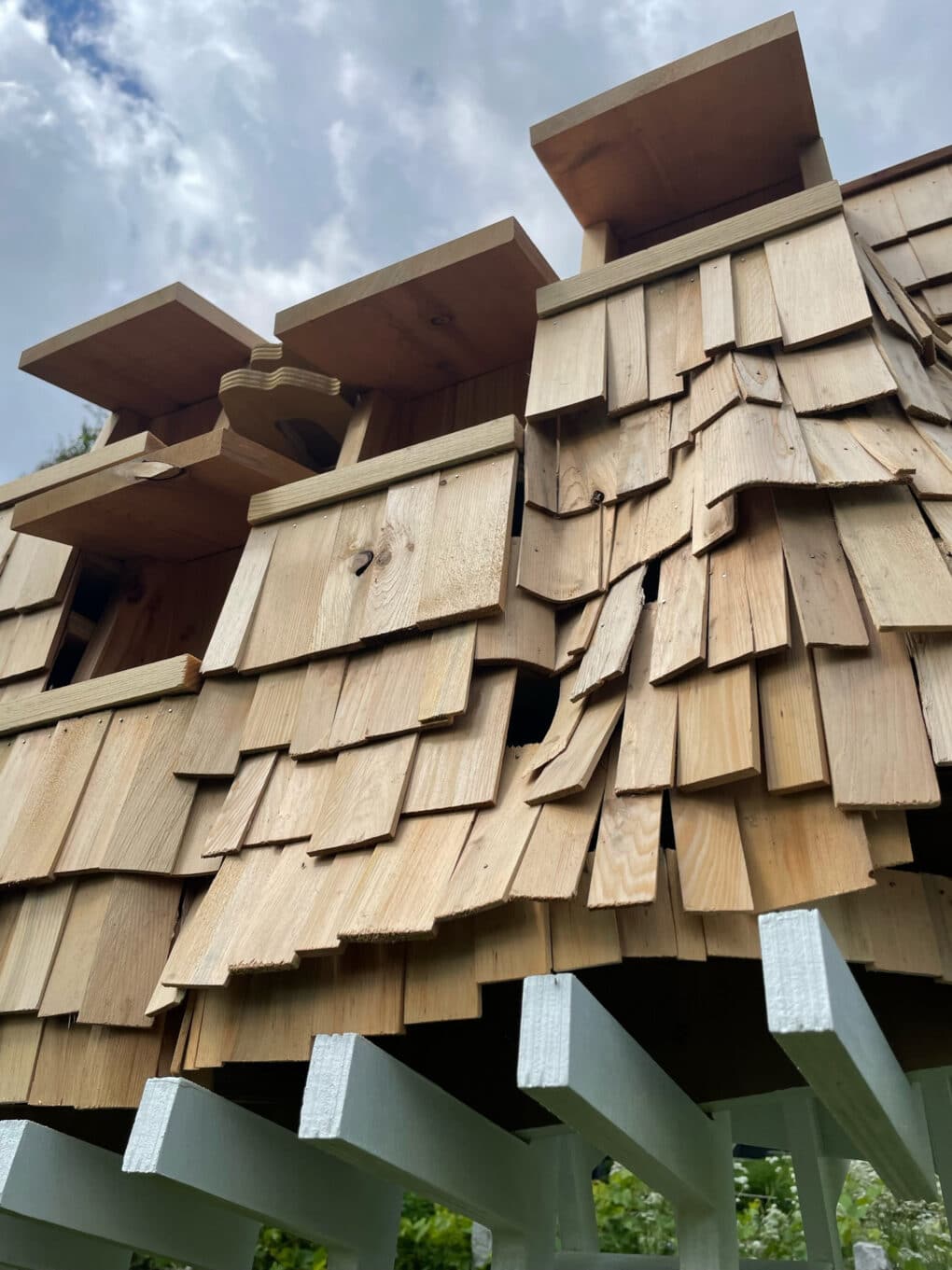 Color photograph of large bird-house built with rippled shingles.