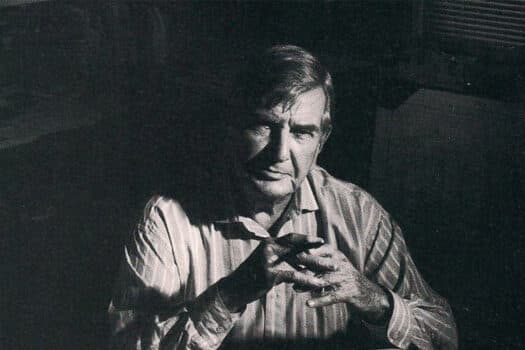 Portrait of Fitch, looking directly into the camera, with dark background.