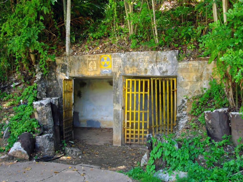 Color photograph of yellow fallout shelter sign on a battered concrete bunker.