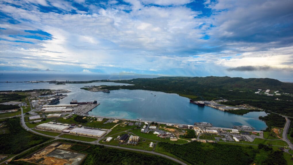 Color aerial photograph of naval base beside a narrow harbor.