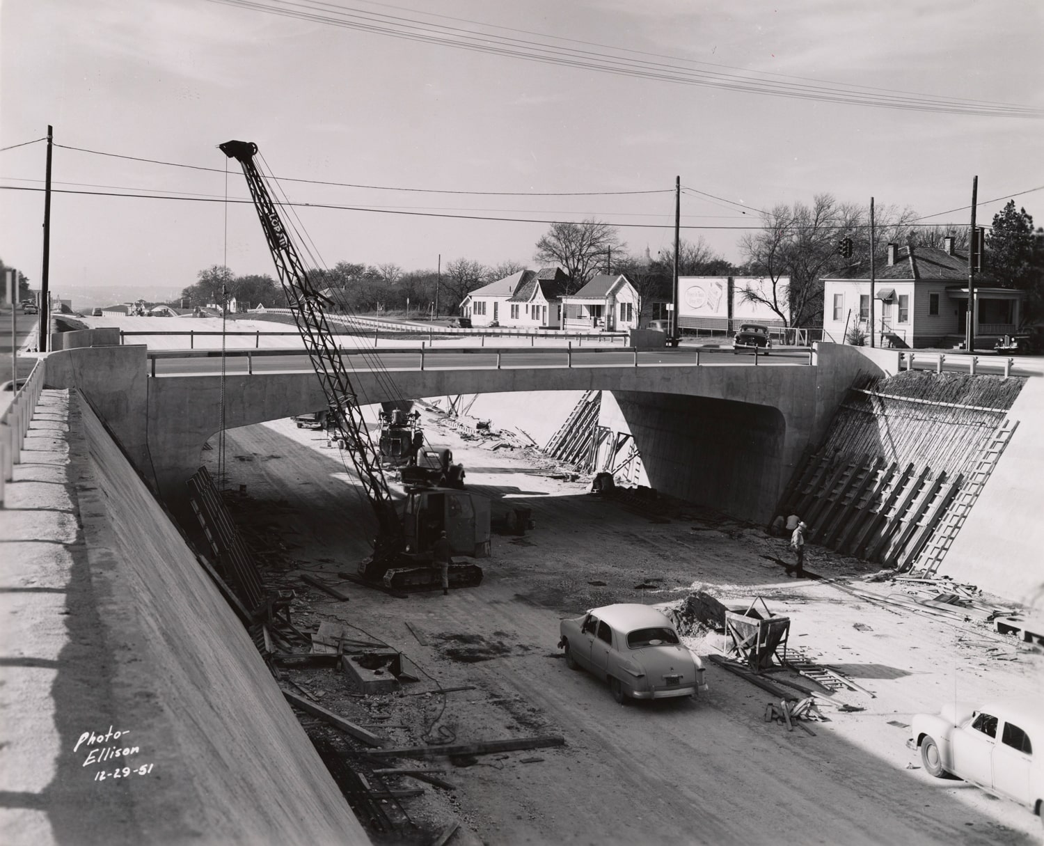 Click to Enlarge Black-and-white photograph of freeway roadbed and overpass under construction.