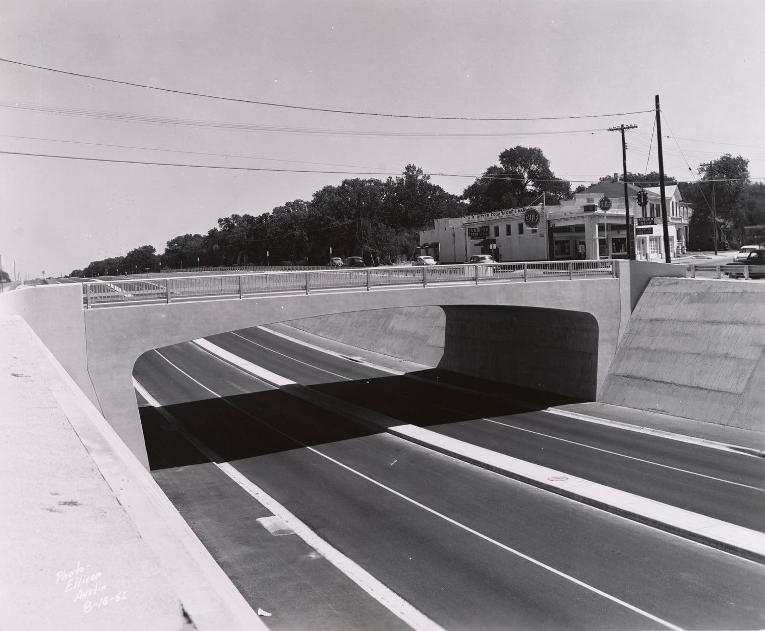 Click to Enlarge Black-and-white photograph of freeway roadbed and overpass.
