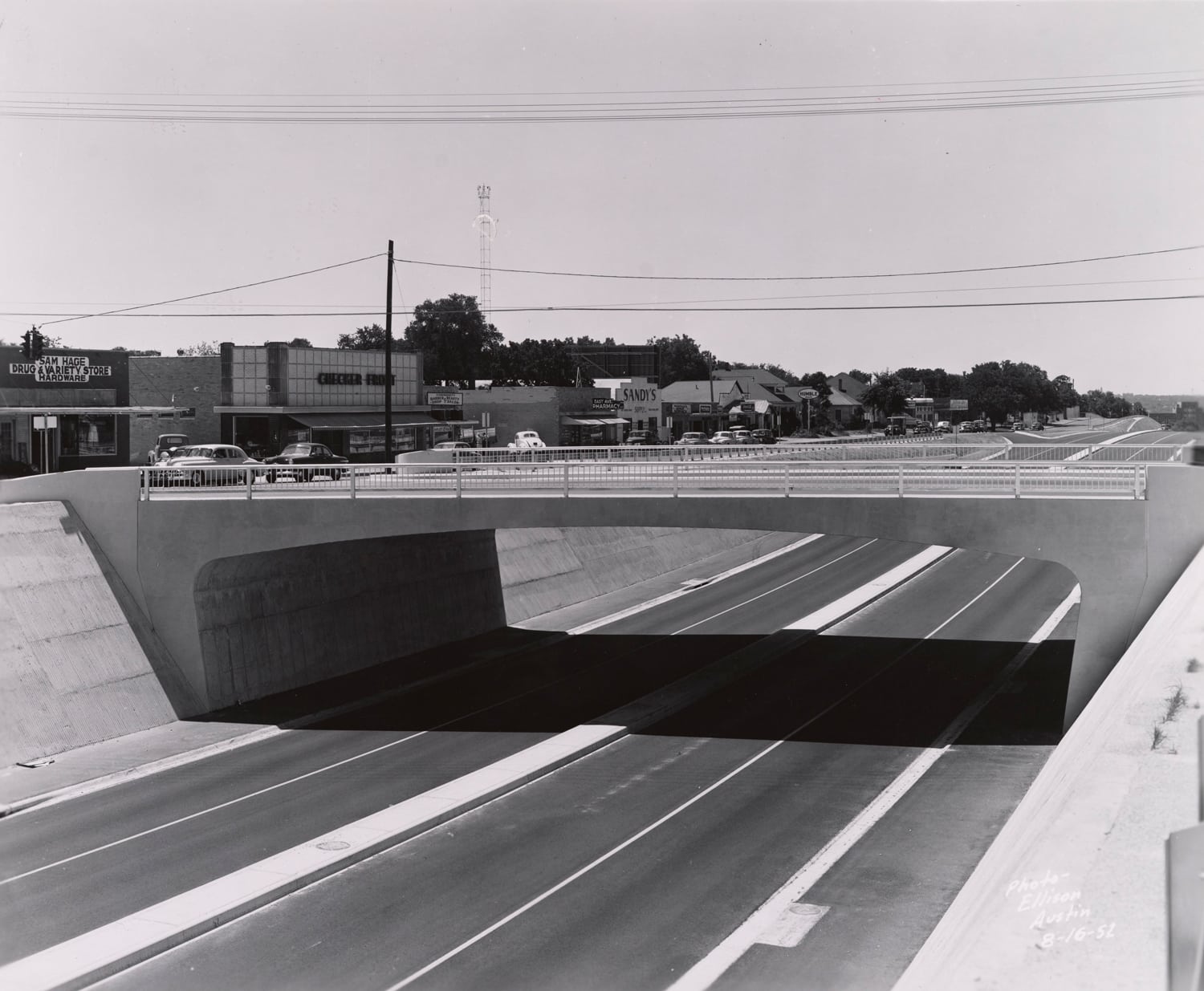 Click to Enlarge Black-and-white photograph of freeway roadbed and overpass.