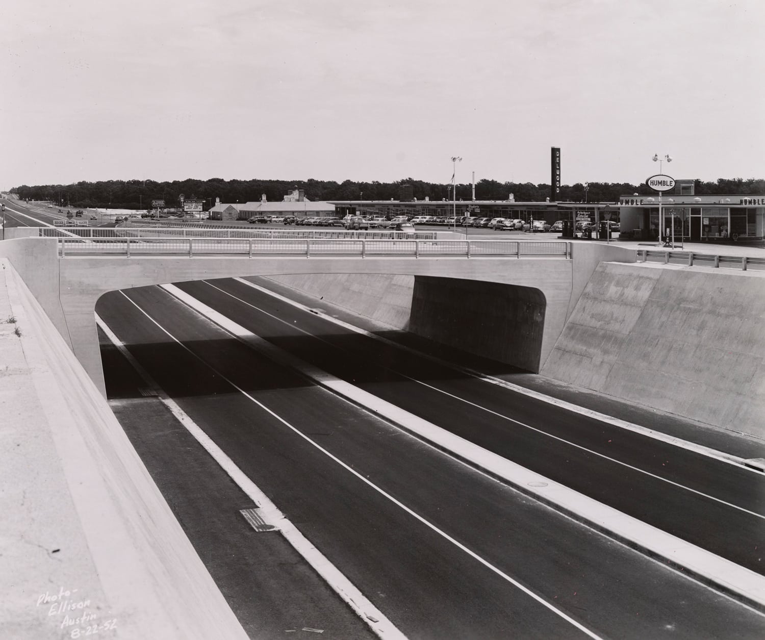 Click to Enlarge Black-and-white photograph of freeway roadbed and overpass.