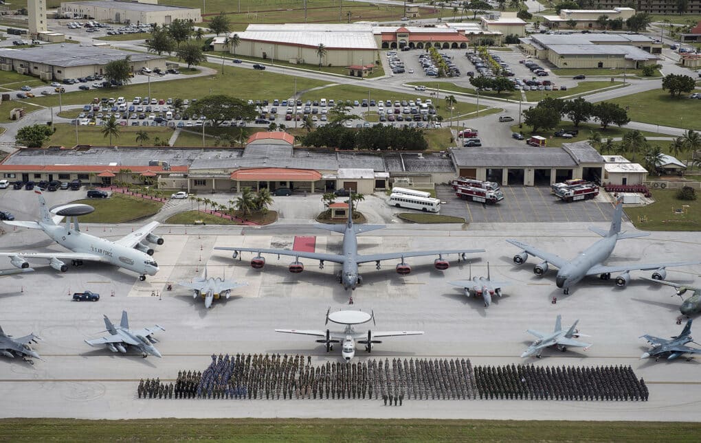 Color aerial photograph of military aircraft and troops in formation on a runway.