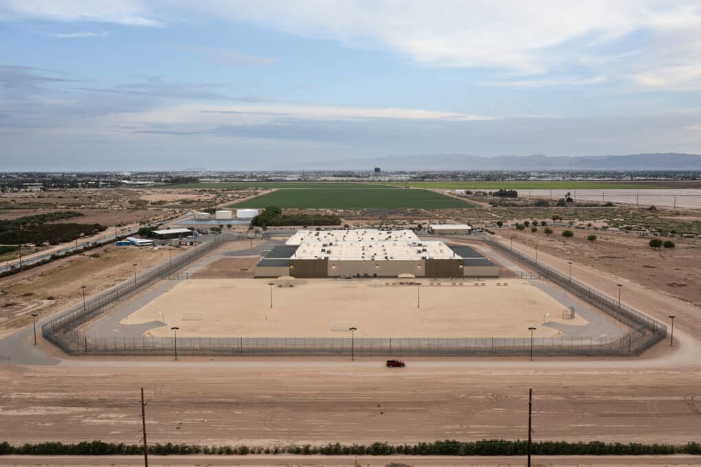Aerial photograph of large prison, showing fence around perimeter and very flat, dry surrounding landscape. 