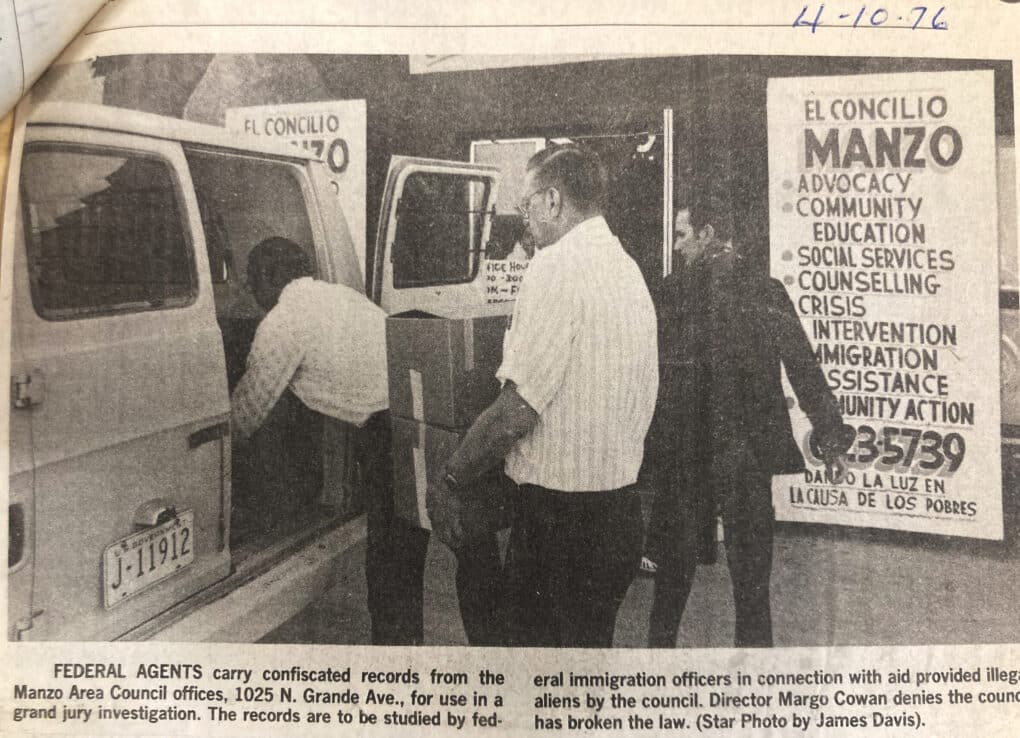 Faded newspaper clipping of three men loading boxes into back of van. 