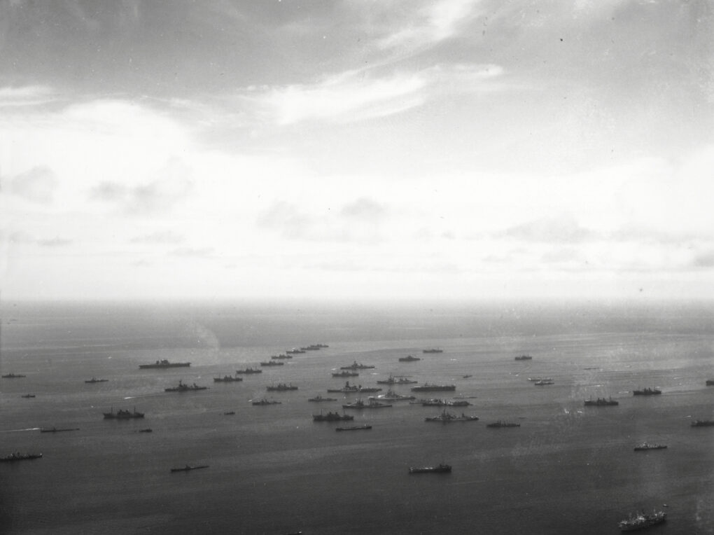 Black-and-white aerial photograph of a fleet at sea.