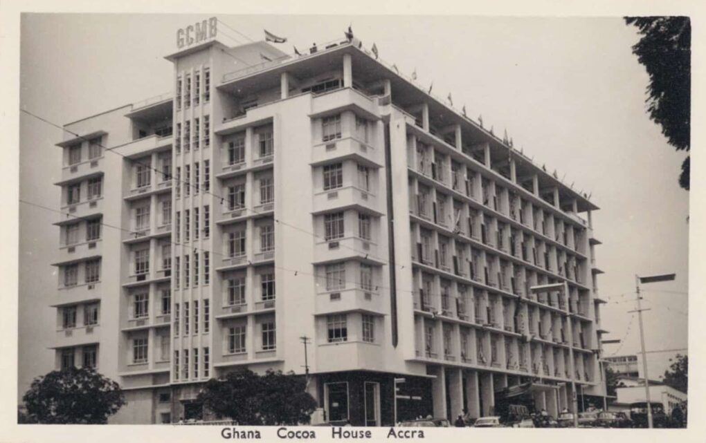 Vintage black and white postcard of 7-story terraced office building, with acronym on roof "GCMB."