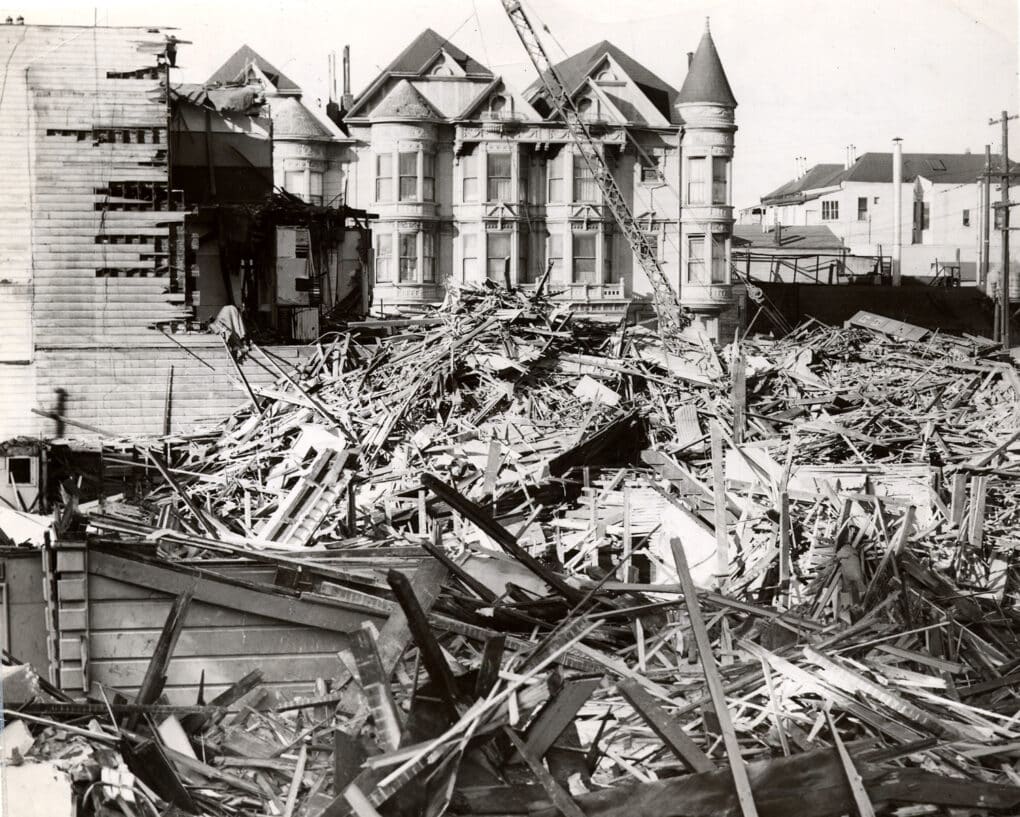 Black-and-white photograph of ornate Victorian houses being demolished.