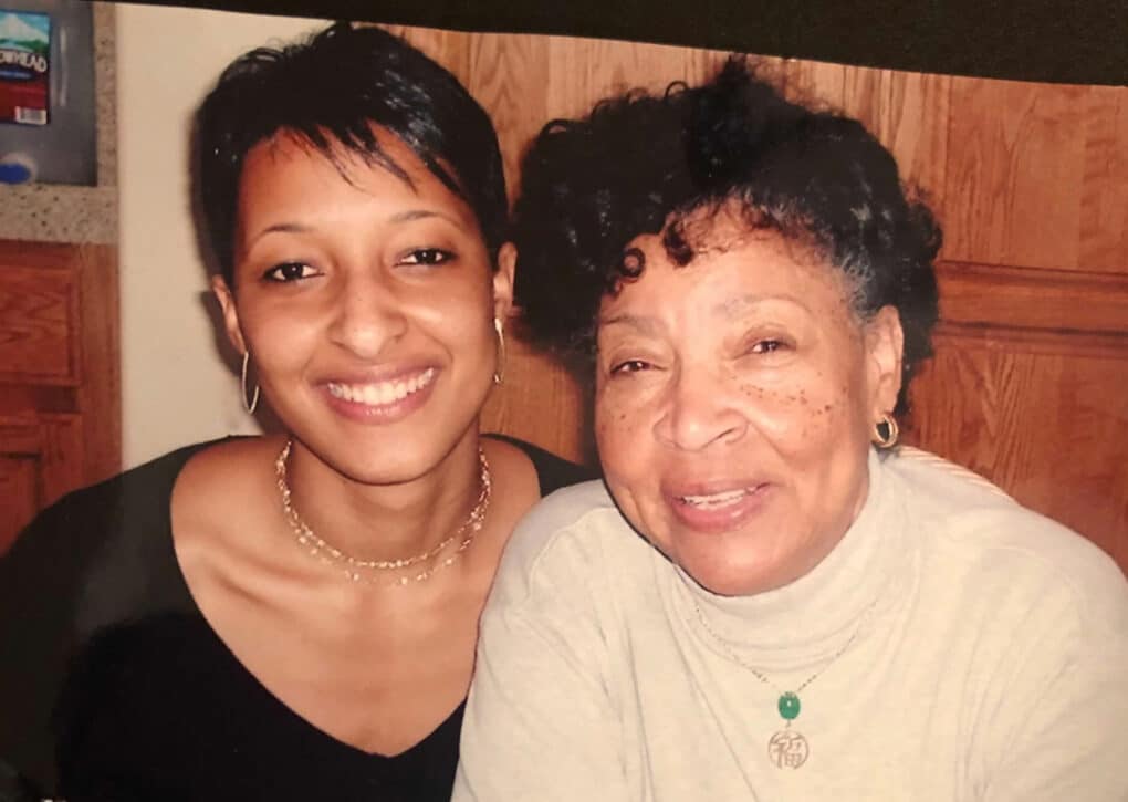 Color photograph of young Black woman and older Black woman smiling at the camera.