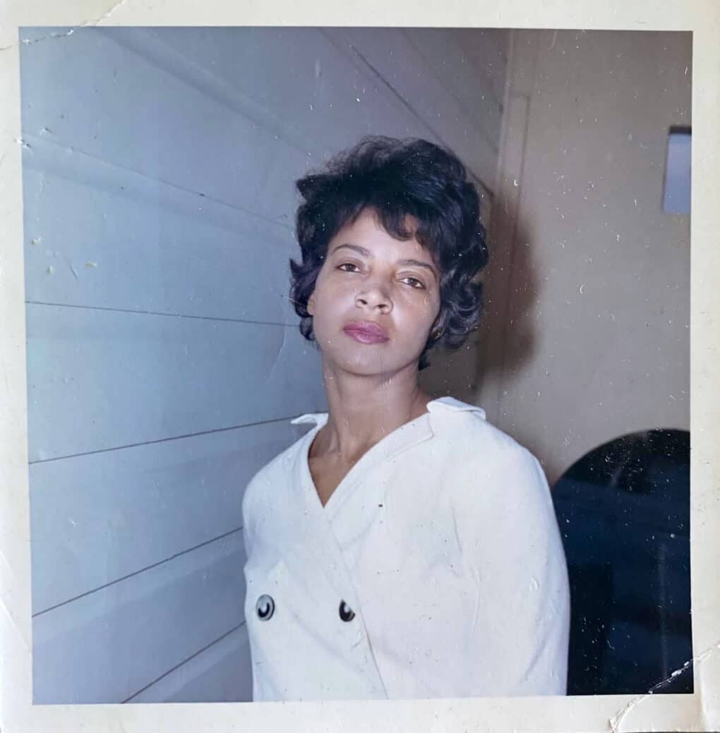Color photograph of beautiful young Black woman in a domestic interior.