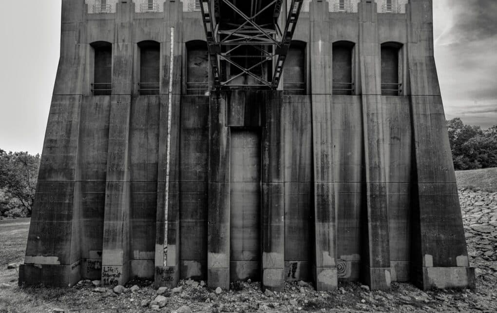 Black and white photograph of an imposing concrete dam structure.