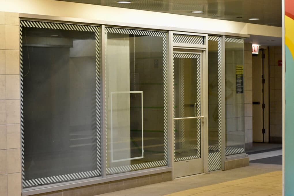 Color photograph of empty storefront in underground corridor.