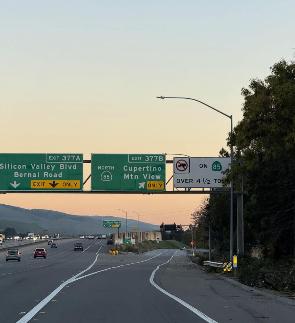 Twilight photo of freeway with very little traffic, showing the exit sign for 85 North, taken from a car.