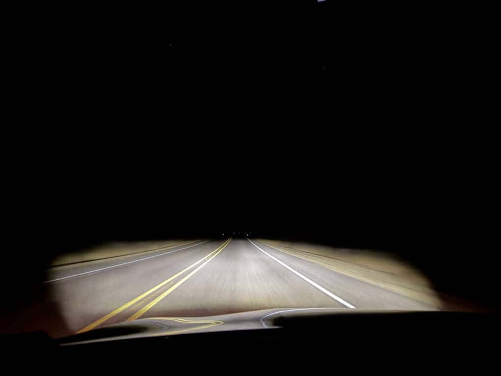 Color photograph taken from inside a moving car on an otherwise deserted road at night.
