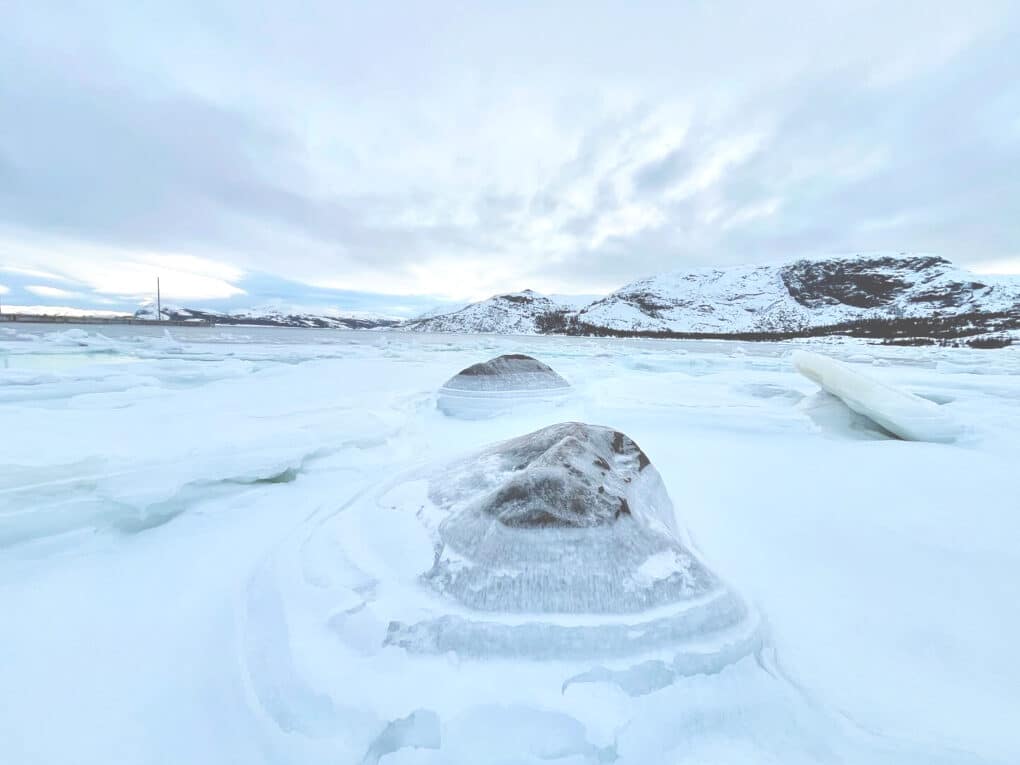Color landscape photo of a very icy frozen waters, with rocks encircled by crystalline ice. 