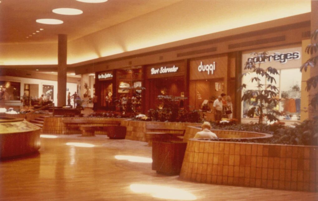 Vintage photo of shopping mall interior, with curved seating areas.